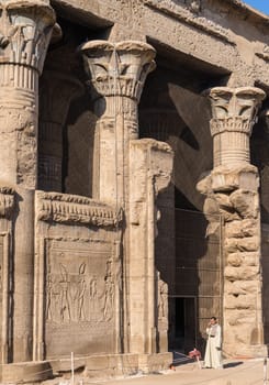 Esna, Egypt - 3 November 2024: Local guide by the entrance to the well-preserved facade of the Temple of Esna, a Greco-Roman temple in Egypt.