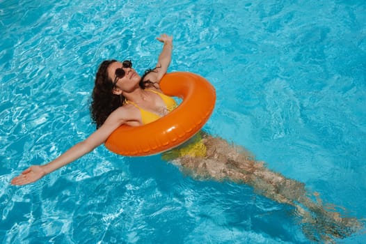 sexy young woman rests in an inflatable circle in pool at a hotel on vacation at a resort in the summer holidays