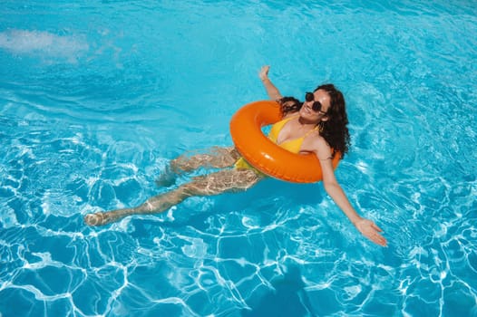young beautiful girl swimming in an inflatable circle in pool at a hotel on vacation at a resort in the summer holidays