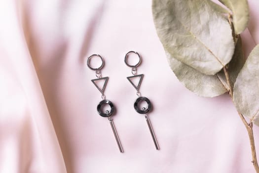 Female Jewelry. Vintage bijouterie jewelry. Beautiful handmade silver earrings on pink silk background. Flat lay, top view copy space and empty space for text.
