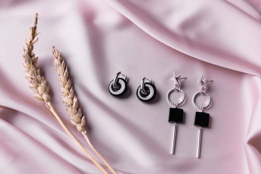 Female Jewelry. Vintage bijouterie jewelry. Beautiful handmade silver earrings on pink silk background. Flat lay, top view copy space and empty space for text.