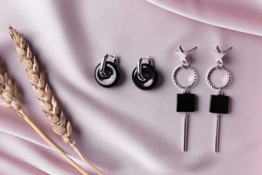 Female Jewelry. Vintage bijouterie jewelry. Beautiful handmade silver earrings on pink silk background. Flat lay, top view copy space and empty space for text.