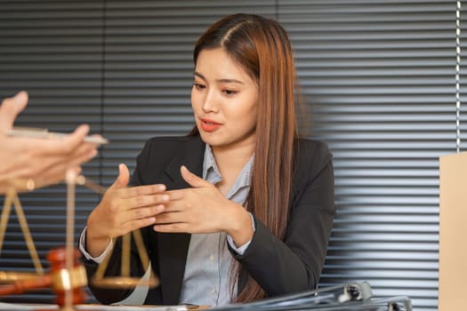 During a consultation, a lawyer explains legal matters intricately with hand gestures to a client, ensuring all information is clear and concise.