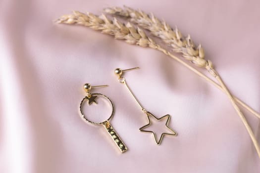 Female Jewelry. Vintage bijouterie jewelry. Beautiful handmade gold earrings on pink silk background. Flat lay, top view copy space and empty space for text.