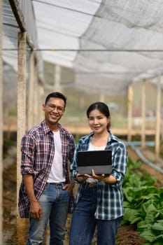 Confident farmers with digital tablet standing in organic farm. Smart farming concept.