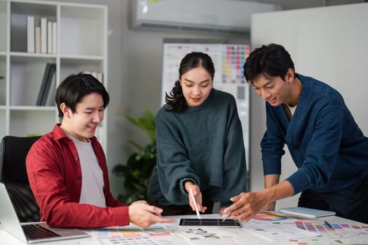A group of designers brainstorms while analyzing color selections and mockups, illustrating their teamwork and creativity in a visually stimulating environment.