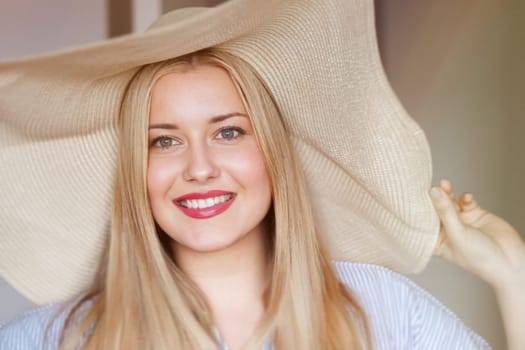 Woman, fashion and summer country charm, blonde beauty and elegance in wide brimmed beach hat. Feminine allure, timeless style and graceful glow. Smile, straw hat and blue striped blouse, natural lighting and effortless charm, fashion look idea