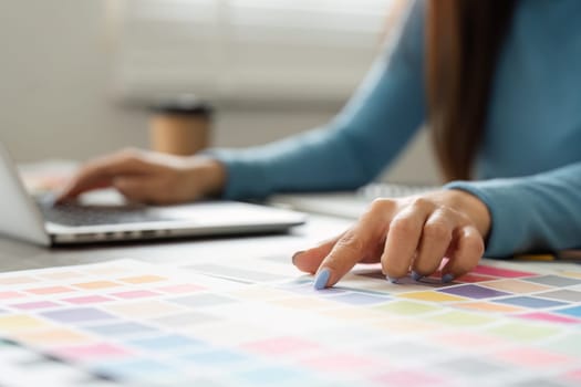 A creative individual is exploring color options, highlighting the blend of digital and physical aspects of design.