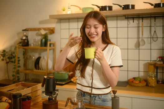 Young woman savoring the aroma of freshly brewed coffee in a cozy kitchen.
