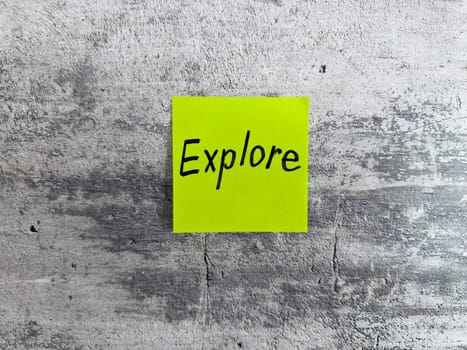 Bright yellow sticky note displaying the word Explore on a textured grey surface, embodying themes of adventure, curiosity, and the excitement of discovering new possibilities