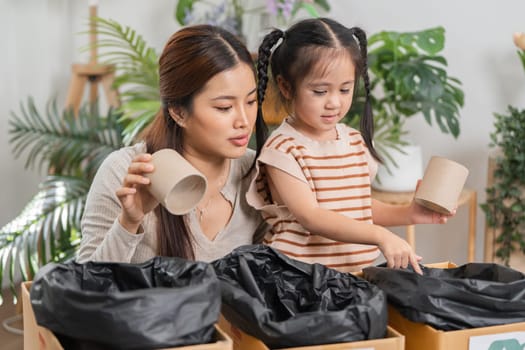 In an engaging home activity, a mother teaches her daughter how to sort different recyclable materials, fostering eco-conscious habits from a young age.