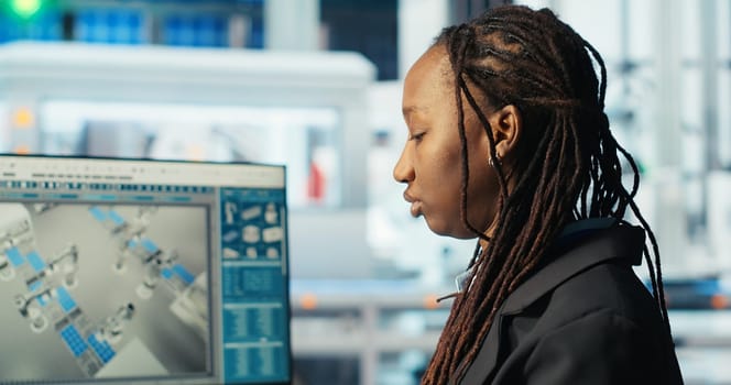 Photovoltaics factory programmer coding on PC to improve solar panels efficiency. African american software developer working in solar panels manufacturing plant, doing research, camera B