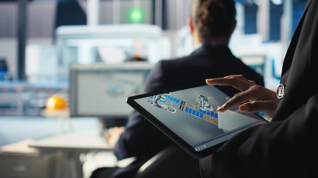 Photovoltaics factory specialist designs production lines in CAD app using tablet. Solar panels plant technician uses simulation software on device to optimize production layouts, camera A closeup