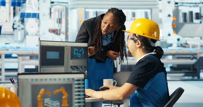 Photovoltaics factory engineer making facility adjustment in CAD program, showing woman. Solar panels plant technician designing assembly lines, informing african american manager, camera B