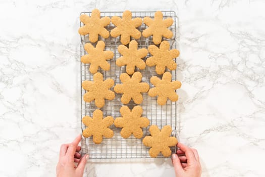 Overhead view of snowflake-shaped amber gingerbread cookies cooling on a wire rack, ready for serving or decoration.