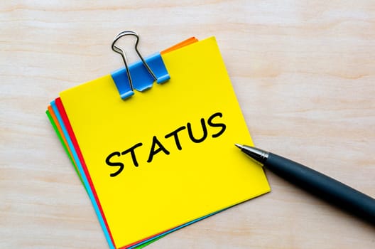 Status text on yellow notepad. Business Updates and status concept.