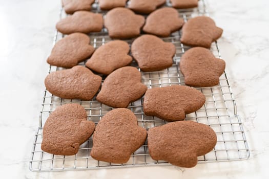 Angled close-up of a cooling rack showcasing baked Pale Gingerbread Cookies in mitten shapes, highlighting their golden-brown texture.