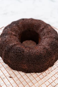 With precision, the Chocolate Bundt Cake is carefully removed from the pan - placed onto a round cooling rack, preparing it for a flawless presentation and delightful indulgence.