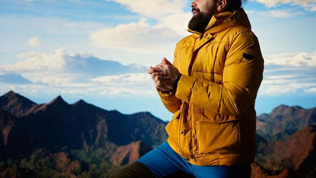Mountain hiker zipping his jacket after climbing to the top with a vast landscape of peaks and sky, embracing the adventure of trekking through the wilderness. Outdoor exploration. Camera A.