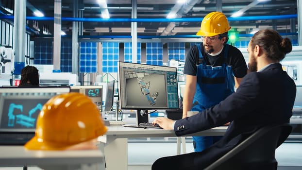 Photovoltaics factory manager showing engineer on PC screen how to adjust system parameters. Specialist showing staff member how to optimize energy supply in solar panel manufacturing plant, camera A
