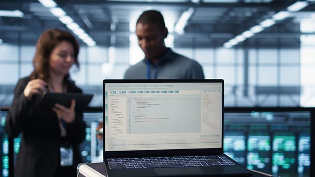 Lines of code on laptop display used by teamworking data center colleagues to run security patches. Programming language on notebook used by server room IT experts scanning gear, camera B close up