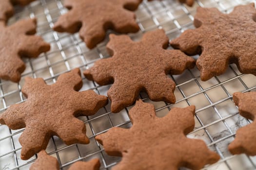 Close-up view of freshly baked Chocolate Ginger Sugar Cookies shaped like snowflakes, cooling on a wire rack. The rich chocolate color and intricate edges stand out beautifully.