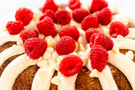 With precision, the White Chocolate Raspberry Bundt Cake is carefully removed from the pan - adorned with luscious cream cheese frosting, creating a delectable treat that is sure to delight.