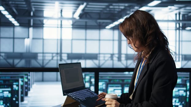Technician using laptop in data center, finetuning network protocols, holding coffee cup. Woman in server room coding on notebook, enforcing advanced security measures, camera B