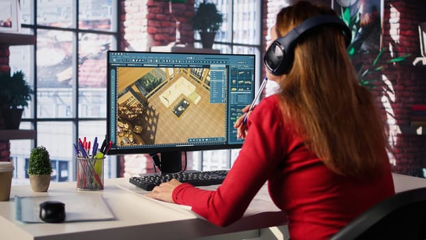 Female employee creates 3D render of an apartment interior using blueprints and architectural software. Employs computer aided tools and models to allow customization of flooring. Camera B.