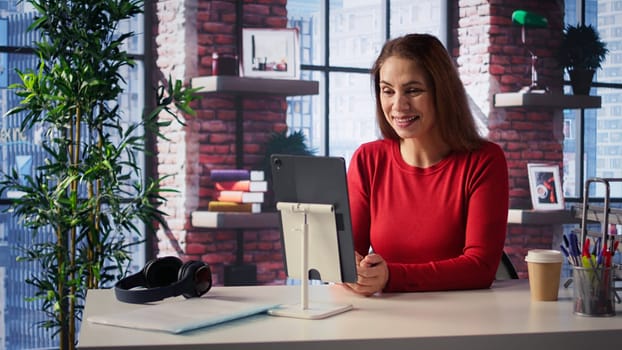 Mature adult participating at a webinar lesson from home office, meeting with a professor via video call connection. Woman studying hard for her master degree remotely, teleconference. Camera B.