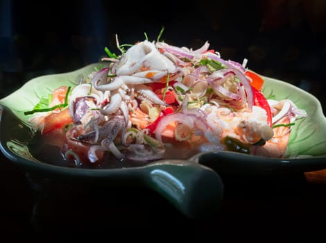 Close-up of Spicy seafood salad with Lemongrass (Thai style spicy) on Ceramic plate. use it as your Wallpaper, Poster and Copy space, Selective focus.