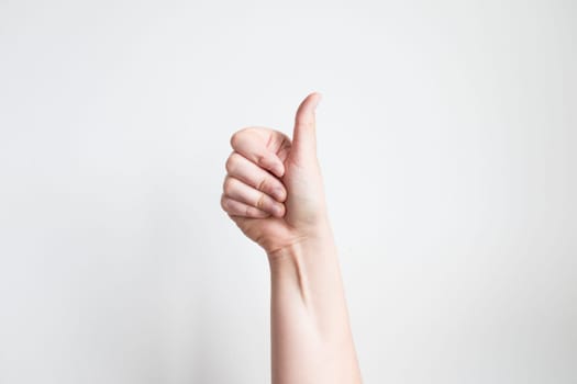 Caucasian hand giving thumbs up against white background.