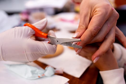 Female manicure process with hands clipping nails close up in salon setting.