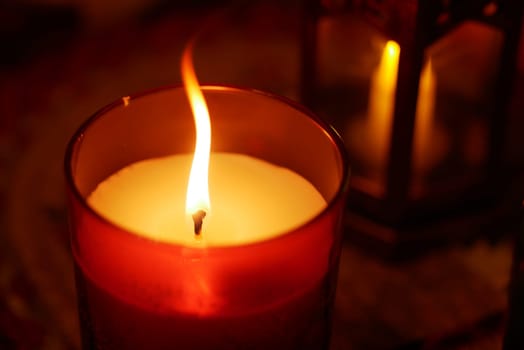 A warm candlelight flickers gently, creating a serene atmosphere indoors.