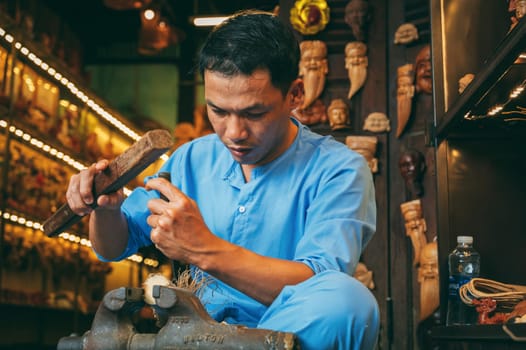 Asian male artisan craftsman carpenter works in a wood carving workshop carpentry on street in Hoi An city in Vietnam in Asia. Hoi An, Vietnam - December 1, 2024