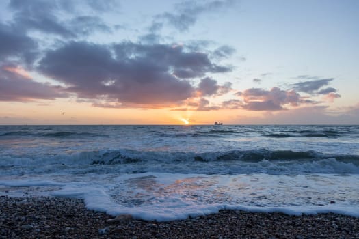 Colorful sunset over the English Channel. Beauty of the sea and ocean, pebbles beach of Normandy, France, Europe