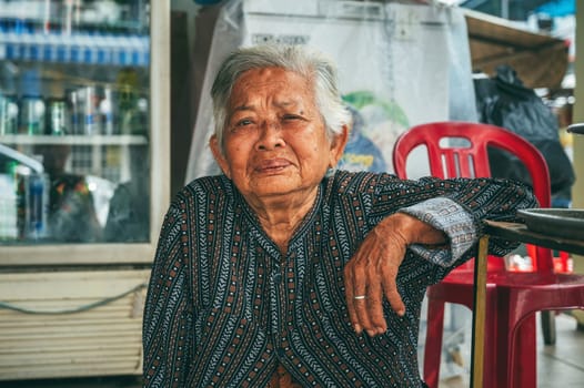 Portrait of an elderly Asian Vietnamese woman on street in the old town in Hoi An in Vietnam in Asia. Hoi An, Vietnam - December 2, 2024