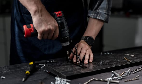 Man Screws Bracket To Shelf With Screwdriver, Hands In Close-Up