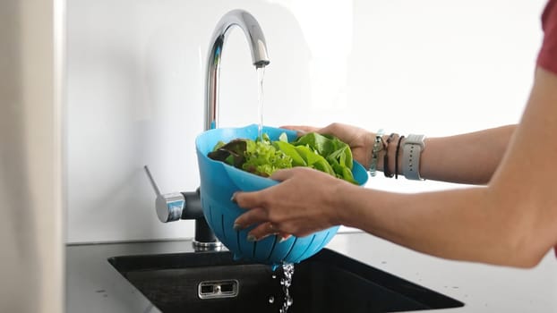 Young Woman In Kitchen Washes Lettuce Leaves In Close-Up View