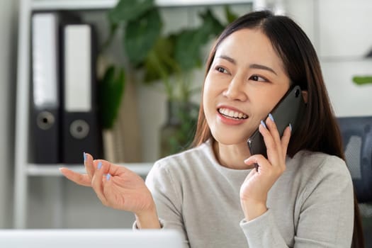 A professional woman talks on her phone with a bright smile, illustrating effective communication while working from home in a well-organized workspace.
