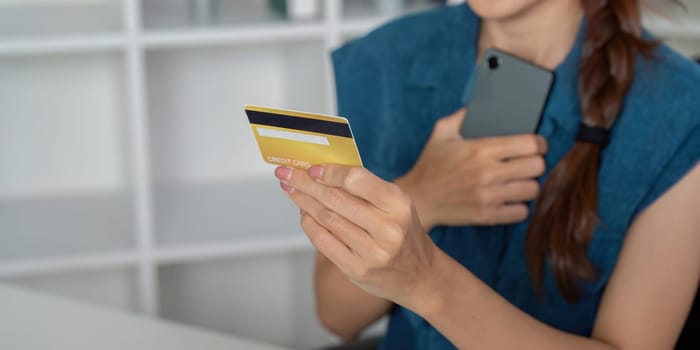 In a contemporary workspace, an individual engages in digital banking using a smartphone and a credit card, highlighting the convenience of online finance management.