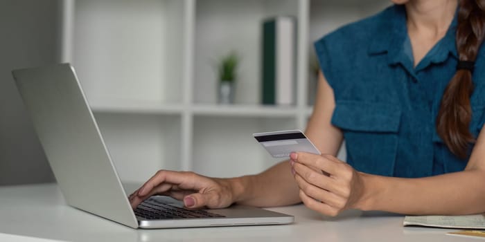 A close-up view of an individual using a laptop alongside a credit card, representing the growing trend of e-commerce and online financial transactions in everyday life.