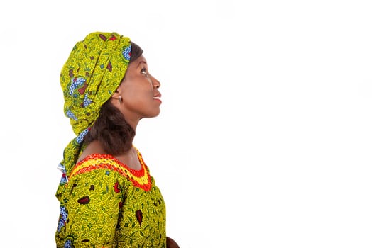 Adult African woman wearing a green loincloth is stopped on one side, with a natural face lifted to the sky and accompanied by a smile