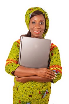 beautiful african adult woman wearing a green loincloth standing, is holding a laptop in her arms smiling