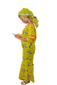 beautiful african adult woman wearing a green loincloth is busy calling, discussing on cell phone side view portrait.