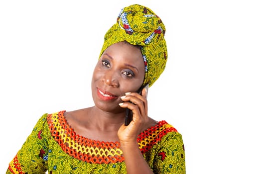 Beautiful African adult woman wearing a loincloth and a green scarf smiles on the phone
