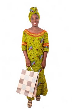 beautiful african adult woman wearing a loincloth and a green scarf is smiling and happy with shopping bags