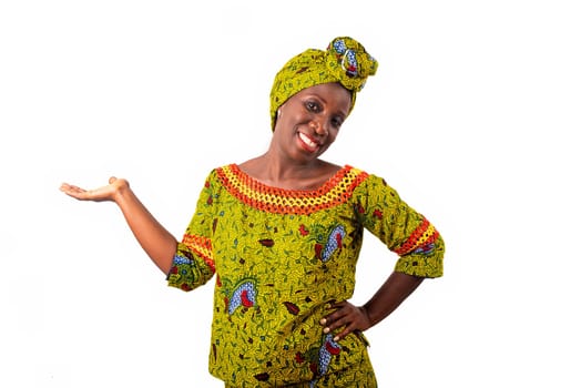 beautiful African adult woman dressed in loincloth and green scarf on the head is smiling with the raised hand and the arm on the hip