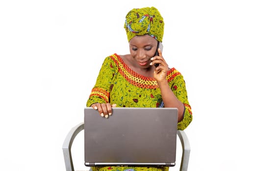 beautiful mature woman sitting in traditional dress on white background communicating and looking at laptop smiling.