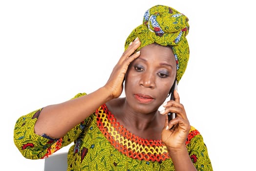 beautiful mature woman sitting in traditional dress on white background communicating on mobile phone.